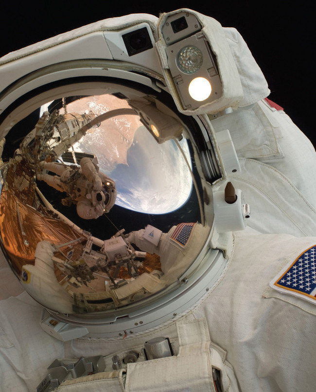 A close-up of Astronaut John Grunsfeld shows the reflection of Astronaut Andrew Feustel, perched on the robotic arm and taking the photo. The pair teamed together on three of the five spacewalks during Servicing Mission 4 in May 2009. The Hubble Space Telescope is a project of international cooperation between NASA and the European Space Agency. NASA's Goddard Space Flight Center manages the telescope. The Space Telescope Science Institute conducts Hubble science operations. Goddard is responsible for HST project management, including mission and science operations, servicing missions, and all associated development activities.